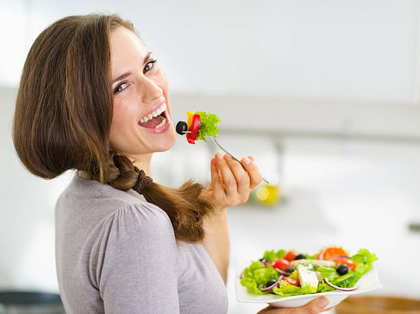 istock Smiling young woman eating salad in modern kitchen 177461764