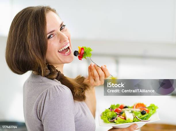 Smiling Young Woman Eating Salad In Modern Kitchen Stock Photo - Download Image Now - Eating, Salad, Women