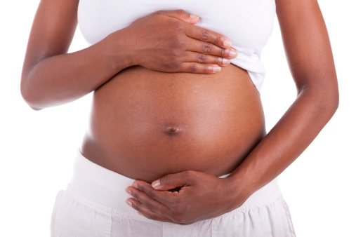 Young pregnant black woman touching her belly, isolated on white background - African people