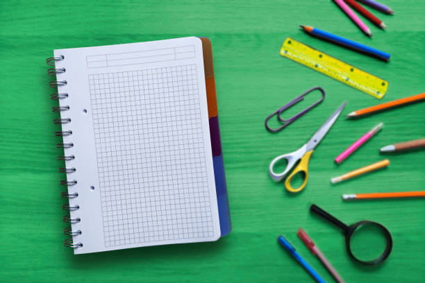 istock Blank open notepad on the background of a green table with stationery. Place for text. 1774646486