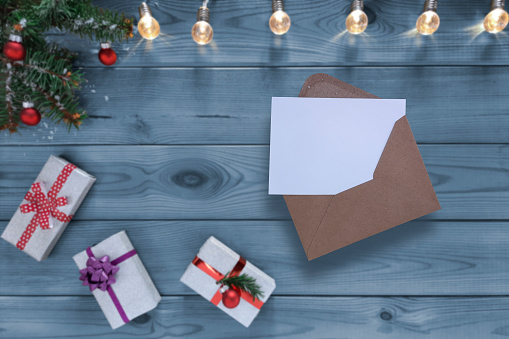 Open envelope with a blank sheet on background of New Year's gifts. Festive atmosphere in the house. Copy space. Template for New Year greeting card.
