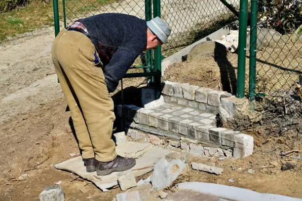 Photo of Bricklayer assembles and bricks the stairway around the house from concrete blocks