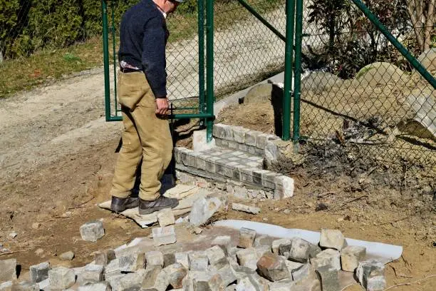 Photo of Bricklayer assembles and bricks the stairway around the house from concrete blocks