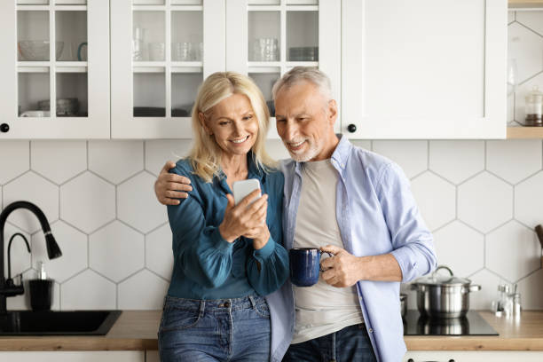 istock Happy Senior Couple Using Smartphone Together While Relaxing In Kitchen At Home 1774689172