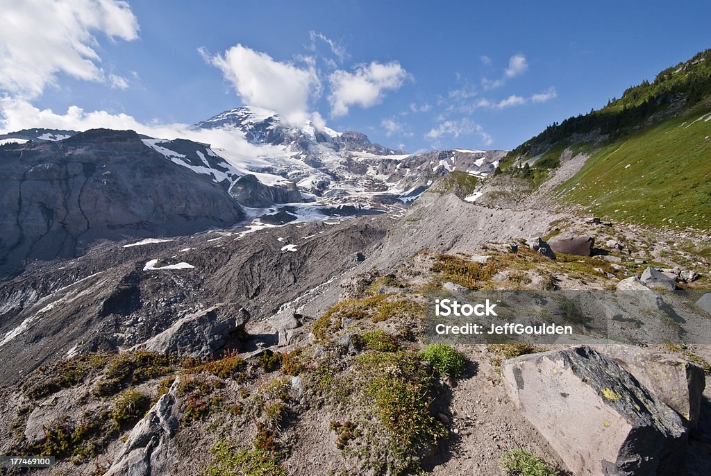 Lateral Moraine of the Nisqually Glacier Glaciers form when snow accumulates over many years and eventually compacts into ice. The weight of the ice causes the glacier to slowly flow down a mountain, cracking along the way to form crevasses. Mount Rainier’s 25 glaciers makes it the most glaciated mountain in the lower 48 states. The 25 glaciers have a combined area of 35 square miles. As glaciers move down the mountain, they scour the landscape leaving boulder strewn fields called moraines. The lateral moraine of the Nisqually Glacier was photographed from Paradise on the south side of Mount Rainier National Park, Washington State, USA. Beauty In Nature Stock Photo