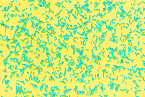 flat lay of blue sprinkles over yellow background, festive decoration for banner, poster, flyer, card, postcard, cover, brochure, designers.