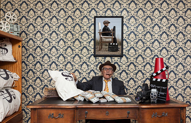 Retired senior man posing with dollar bills and cinema equipments