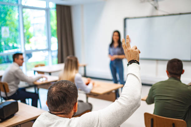 istock Student sitting in a classroom asking female professor a question 1774732286