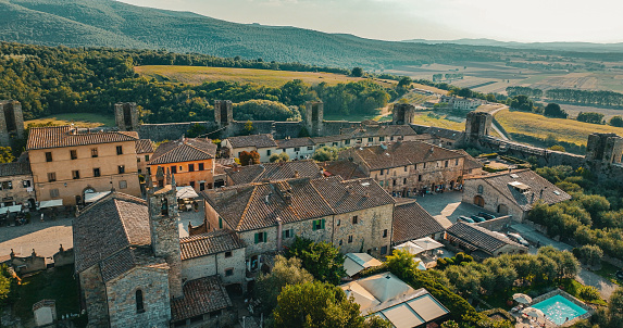 Monteriggioni shines from the top of a hill with its stone crown. One of the oldest, most memorable and recognizable villages in all of Italy, it seems that it has been inhabited since the eighth century BC. A true mirage for those who want to dive into the Middle Ages, the town is even mentioned by the Supreme Poet Dante Alighieri in the Divine Comedy: Inferno, Canto XXXI.\nIt's a place that has remained incredibly intact as if time has never passed, even though it was built by the Sienese between 1213 and 1219 for defensive purposes. The village dominates the territory from the top of a hill overlooking the Via Cassia, a strategic position from which to control the Valdelsa territory.