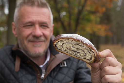 Man eats poppy seed roll outdoors