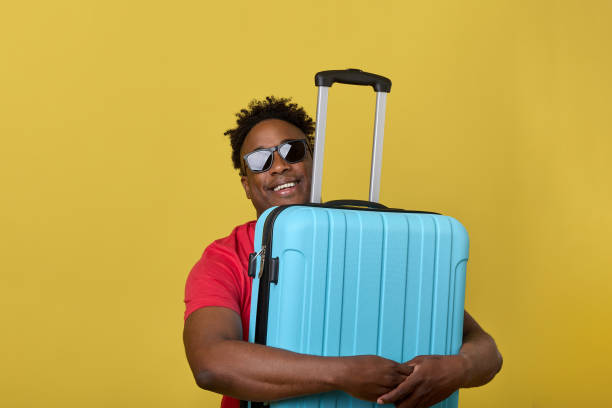 istock Dark-skinned man cheerfully and easily wrapped hands around blue travel suitcase 1774815921