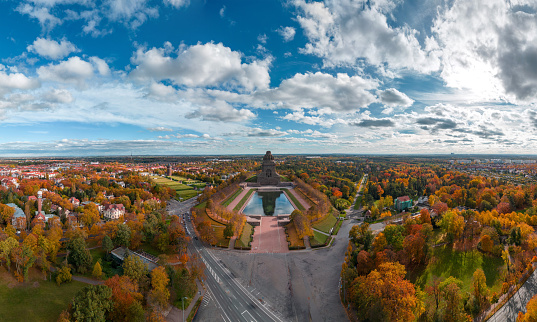 Panorama of the Leipzig Monument to the Battle of the Nations in fall 2023 with orange leaves and blue sky