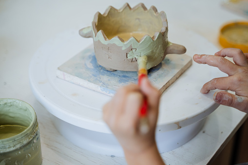 The child is engaged in a potter's wheel. Pottery Workshop. sculpt from the clay pot. creativity for children. fine motor skills of the hands. four hands.