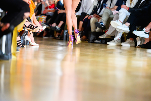 Low section of fashion model walking on catwalk during fashion week, copy space