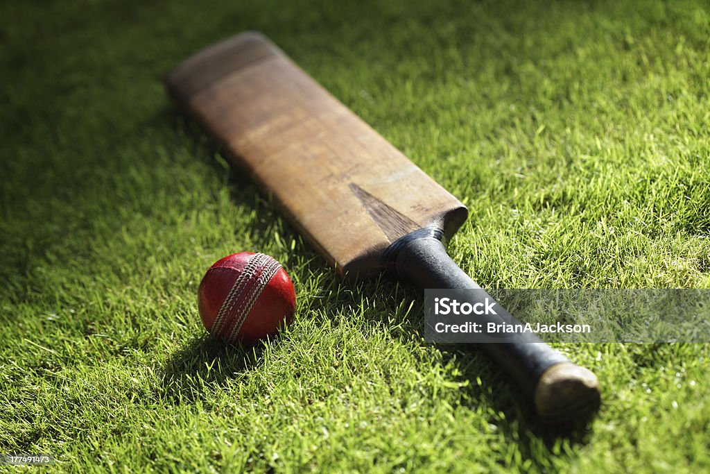 Cricket bat and ball Cricket bat and ball on green grass of cricket pitch Cricket Bat Stock Photo