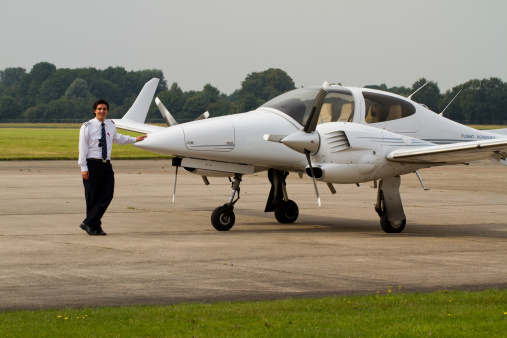A young student pilot posing in front of the flight school's two-engined aircraft. Airplane is a Diamond DA-42 twinstar.