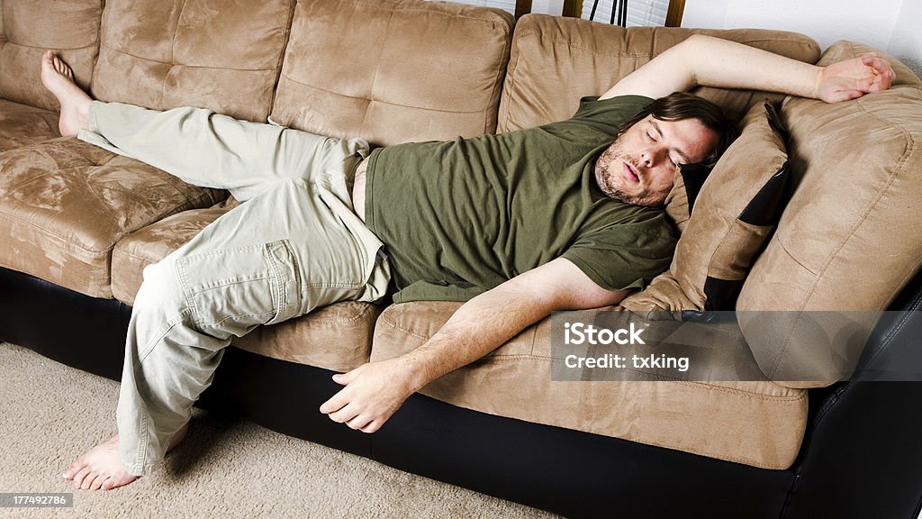 Lazy guy alejadas todo el sofá en la sala de estar - Foto de stock de Couch Potato - Refrán en inglés libre de derechos