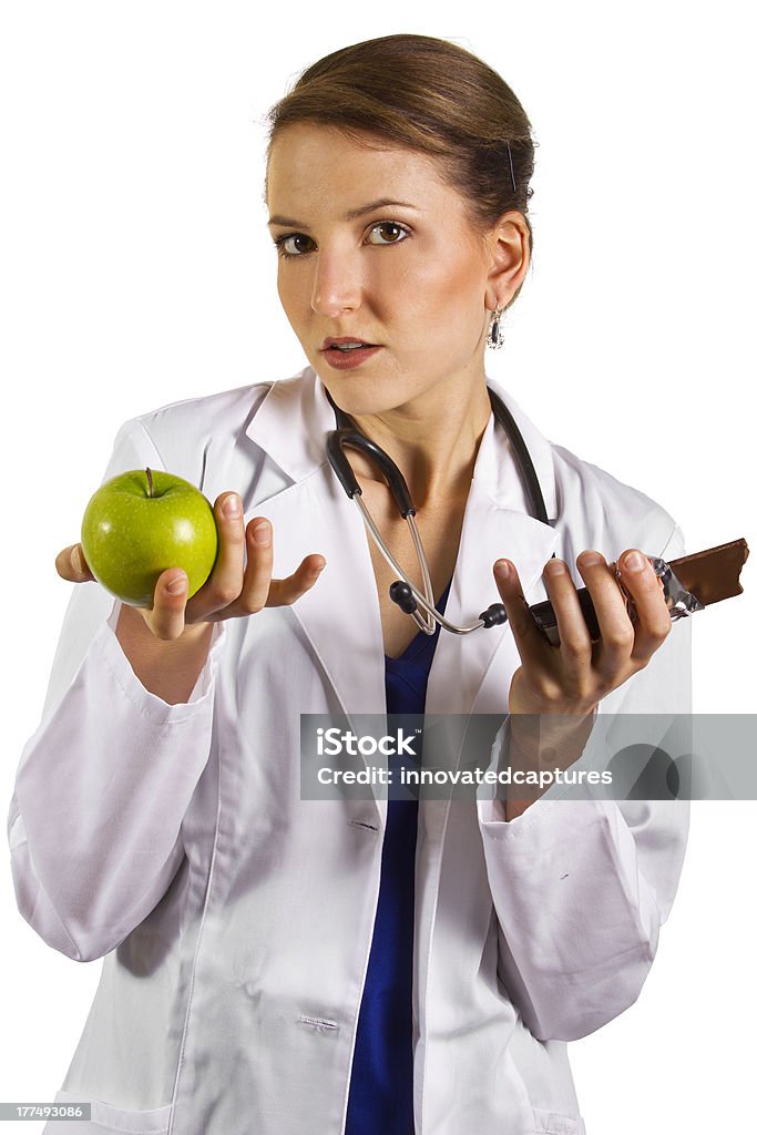 Femmina nutrizionista tenendo una mela e una barretta di cioccolato - Foto stock royalty-free di Adulto
