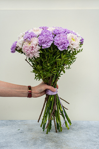 Beautiful bouquet with pale purple carnation and Chrysanthemum flowers in the woman hands