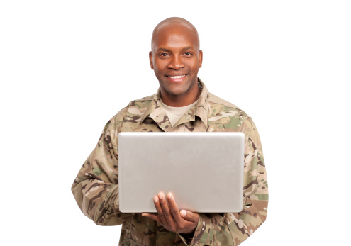 An african american serviceman smiles while holding a laptop computer 