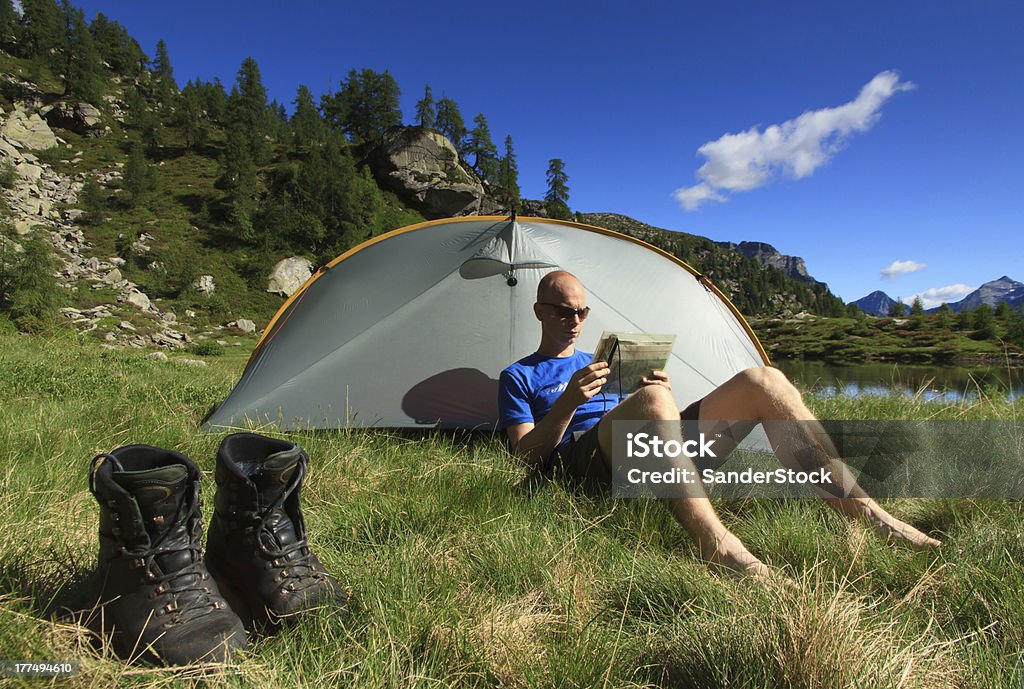 Relaxing feet Hiker in the mountains relaxing his feet and reading a map in front of his tent. Hiking Stock Photo