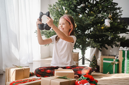 Girl celebrating Christmas at home unpacking gifts