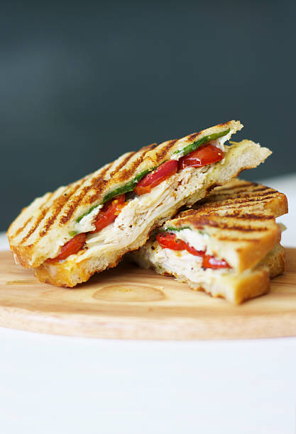 Grilled Chicken Panini "A grilled chicken breast panini sandwich with melted cheese, arugula, roasted tomatoes, and pesto mayo on sourdough bread." panino stock pictures, royalty-free photos & images