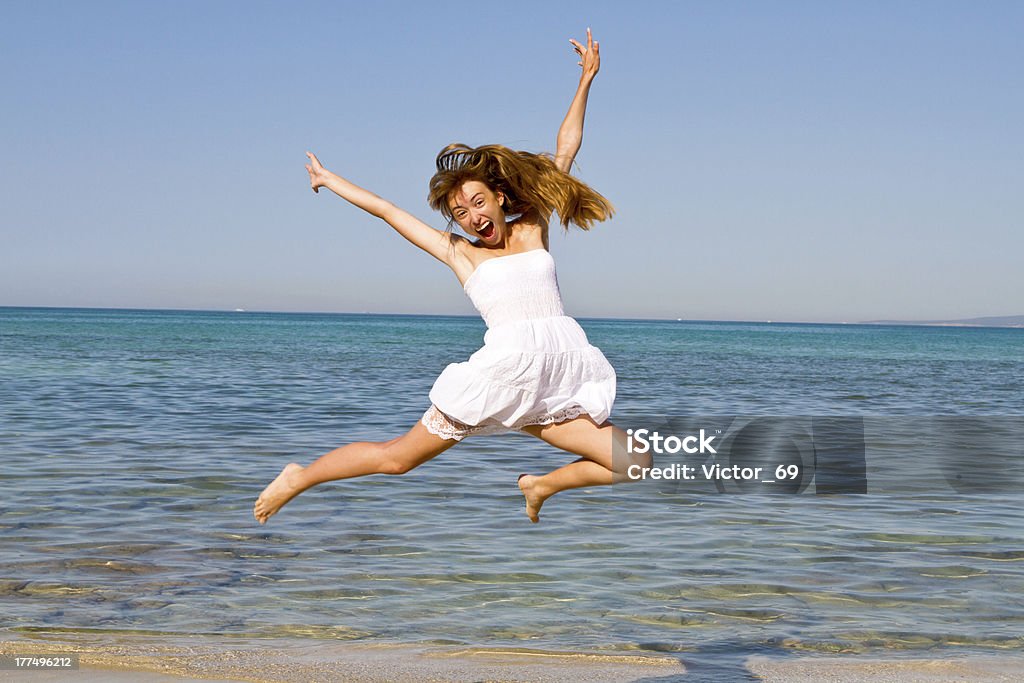 Happy young beautiful woman jumping on the beach Activity Stock Photo