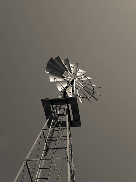 An angled upward black and white view of an old fashioned windmill turbine used for pumping water to the surface.