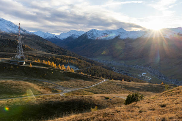 The sun rises over snowcapped mountains and alpine in autumn