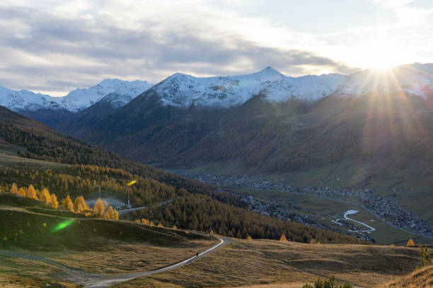 The sun rises over snowcapped mountains and alpine in autumn