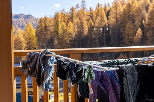 Clothes hand on drying rack on balcony above forest and hills in autumn