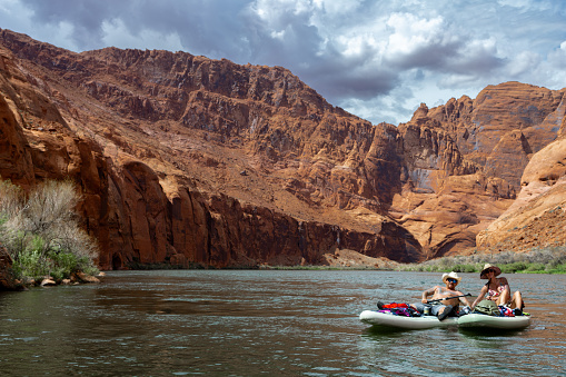 They are floating on a SUP board down a river in summertime