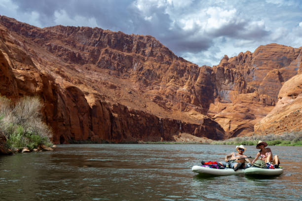 Couple explore desert lands and river together They are floating on a SUP board down a river in summertime horseshoe bend river stock pictures, royalty-free photos & images