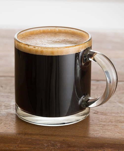 Black coffee and froth in glass mug wood table Black expresso coffee in small glass cup on wooden table cafe transparent glass table stock pictures, royalty-free photos & images