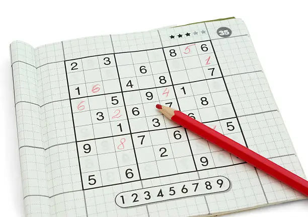 Partially solved Sudoku and red pencil isolated on white