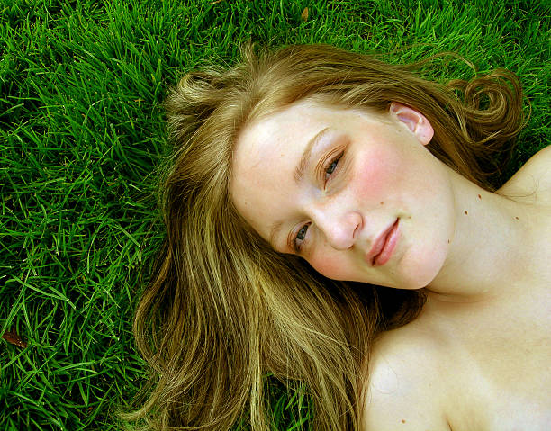 woman with bare shoulders laying in grass outside