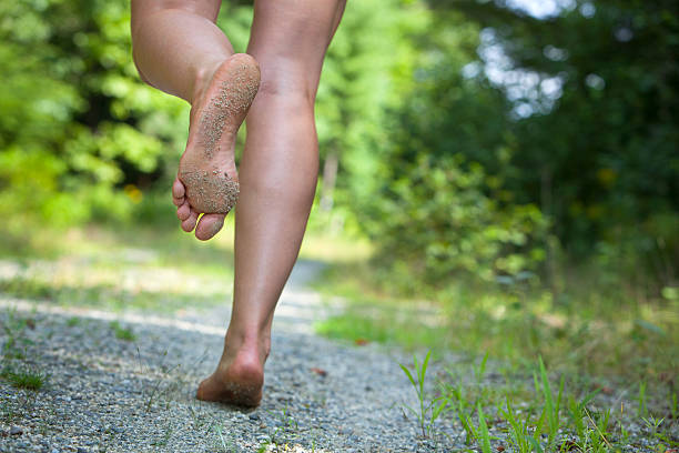 woman's feet running on gravel road closeup of caucasian woman's feet running on gravel road with green woods and vegetation in soft focus. barefoot stock pictures, royalty-free photos & images