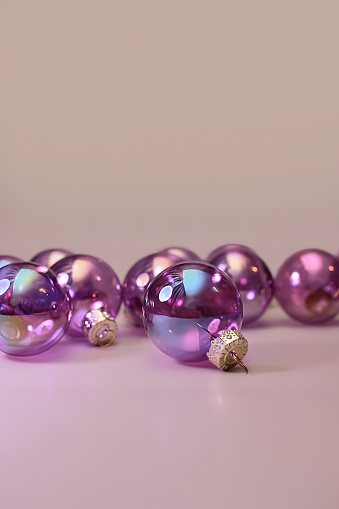a lot of purple transparent glass christmas decoration baubles on beige background. copy space, close up