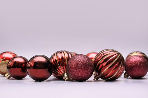 a bunch of burgundy christmas decoration baubles on lilac background. copy space, close up