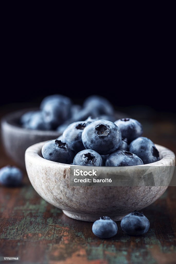 Bilberries in small stone bowls close up of fresh bilberries in stone bowls Blueberry Stock Photo