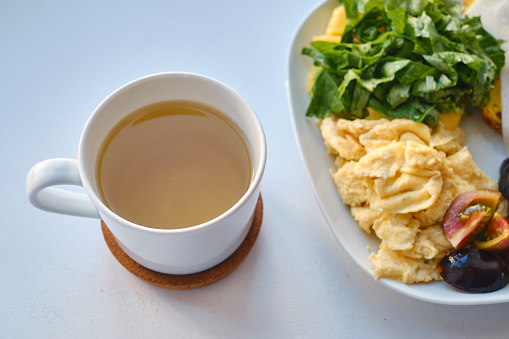 Fresh delicious breakfast with tea, crispy toaster with cheese, omelet and fresh salad on a light background. The concept of proper nutrition. Copy space
