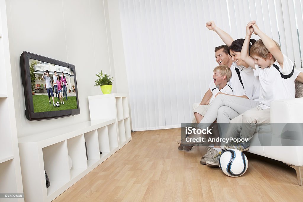 Young family watching football Young family watching football match at home Television Set Stock Photo