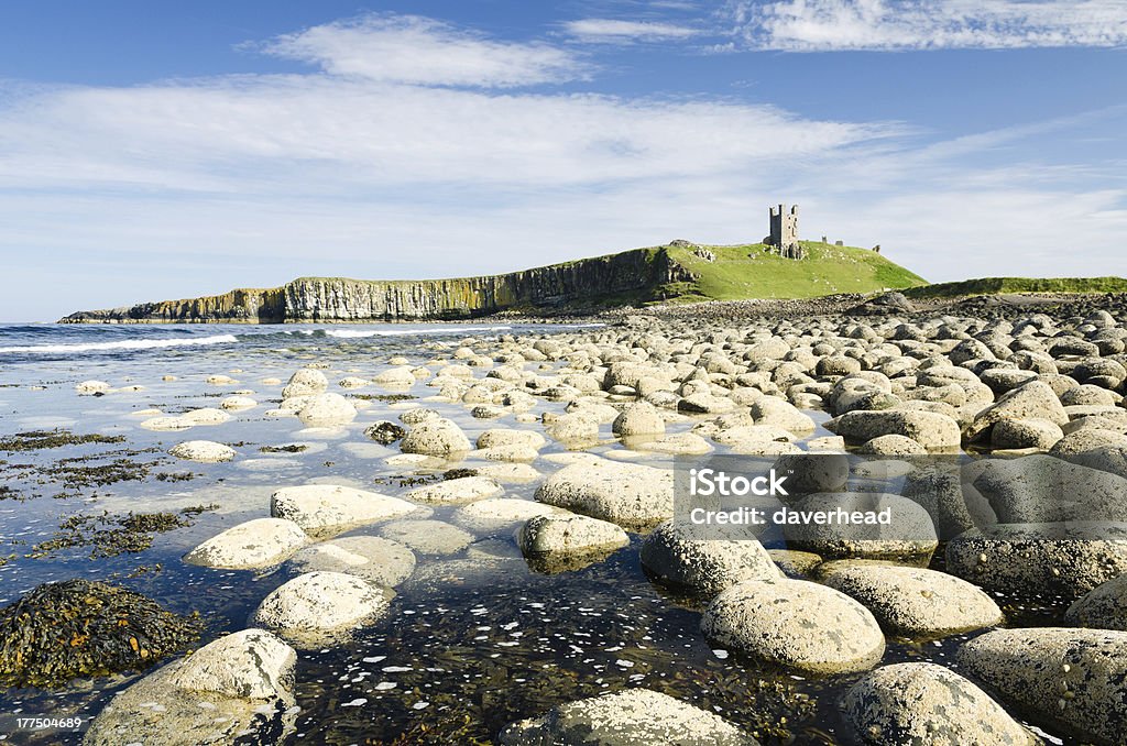 Dunstanburgh Castle Iconic Dunstanburgh castle ruin built in the 14th century viewed from the northern rocky shoreline Northumberland Stock Photo