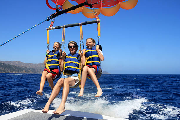 happy family parasailing - parasailing stok fotoğraflar ve resimler