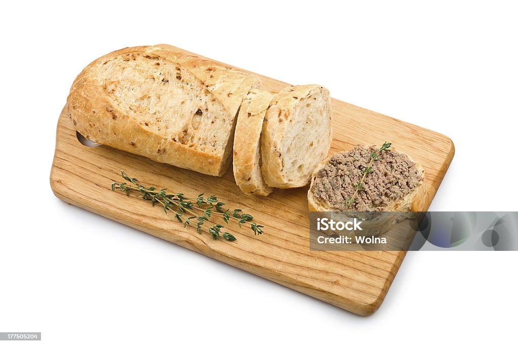 Slice of homemade bread with pate and herbs Slice of homemade bread with pate and herbs on a wooden cutting board isolated on white background Baguette Stock Photo