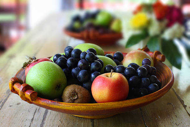 Fruit Basket on Wooden table "A traditional, handmade basket/bowl with fruits from garden and market (kiwi)." fruit bowl stock pictures, royalty-free photos & images