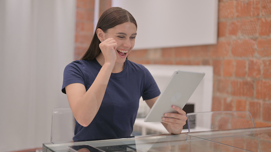 Young Latina Woman Celebrating Success on Tablet PC
