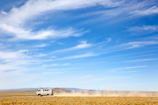 a van across the desert at high speed leaving a trail of dust