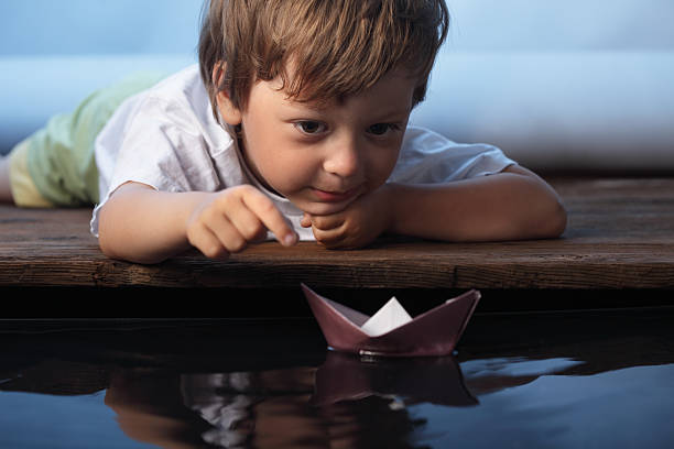 A little boy floating a paper ship paper ship in children hand toy boat stock pictures, royalty-free photos & images
